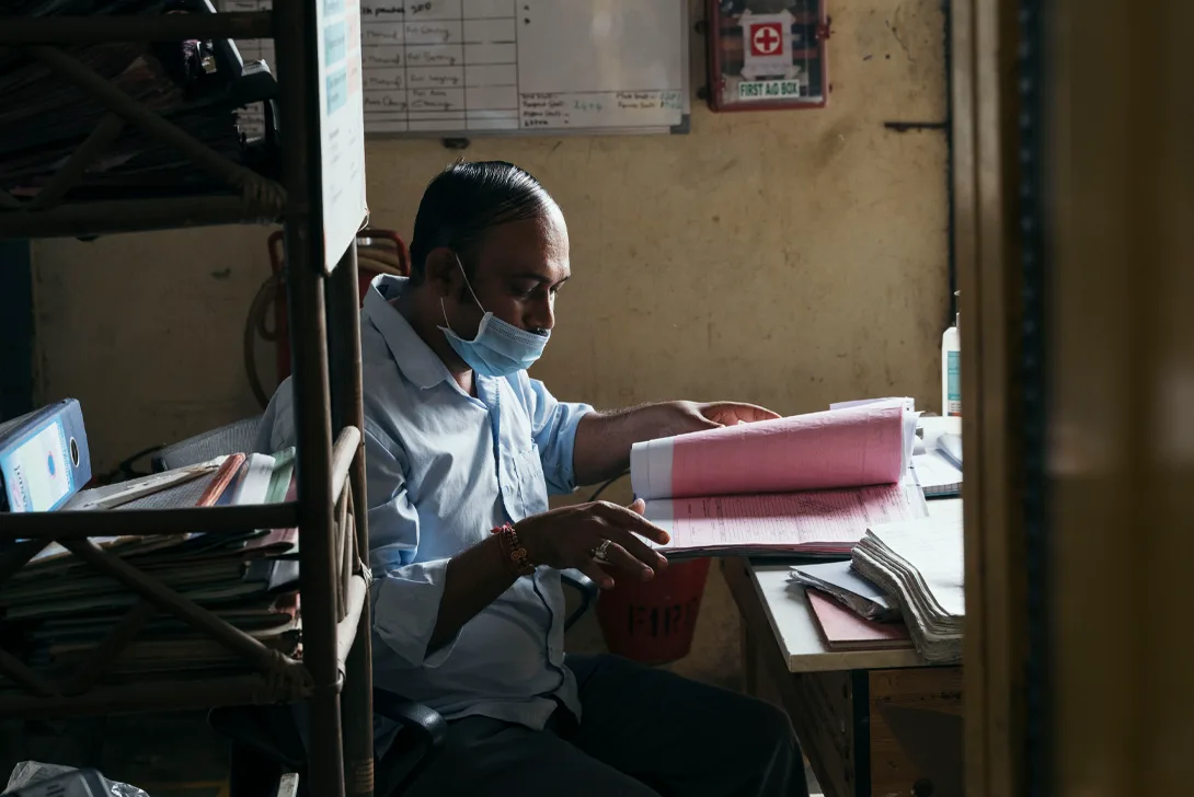 A man wearing a face mask works at a desk (Photo)