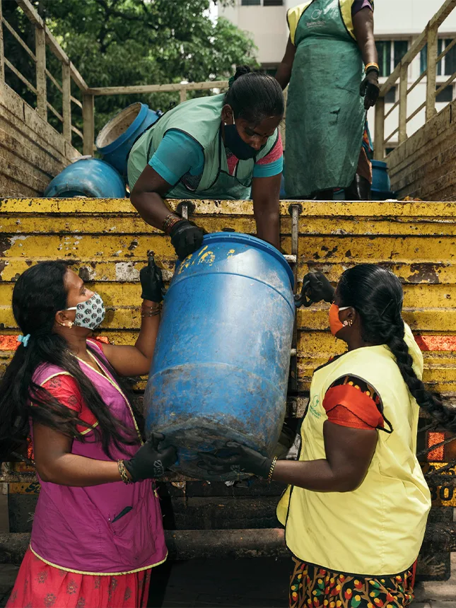 Three women helping each other to lift a canister onto a transporter (Photo)