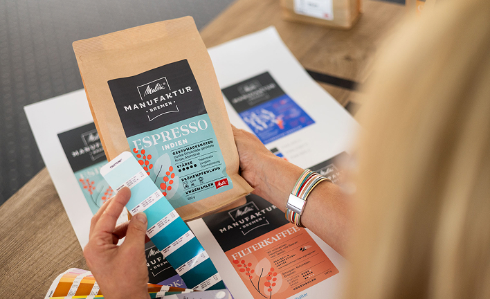 Protagonist compares a package of espresso from Melitta Manufaktur Bremen to a Pantone color fan.