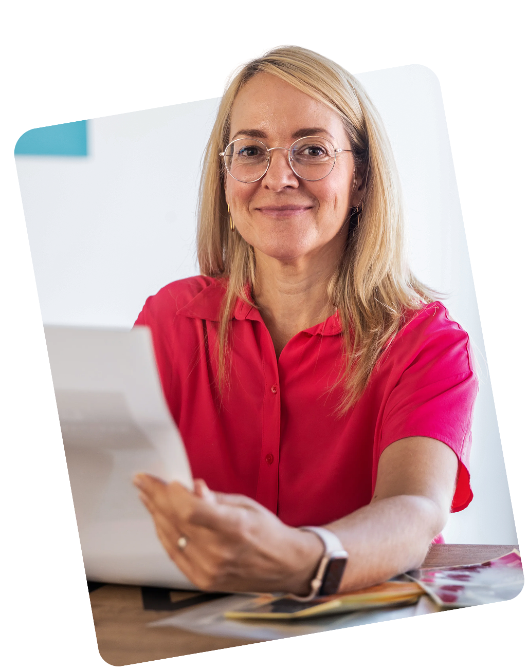 Portrait of the blonde protagonist sitting at a wooden table, holding a design sketch.