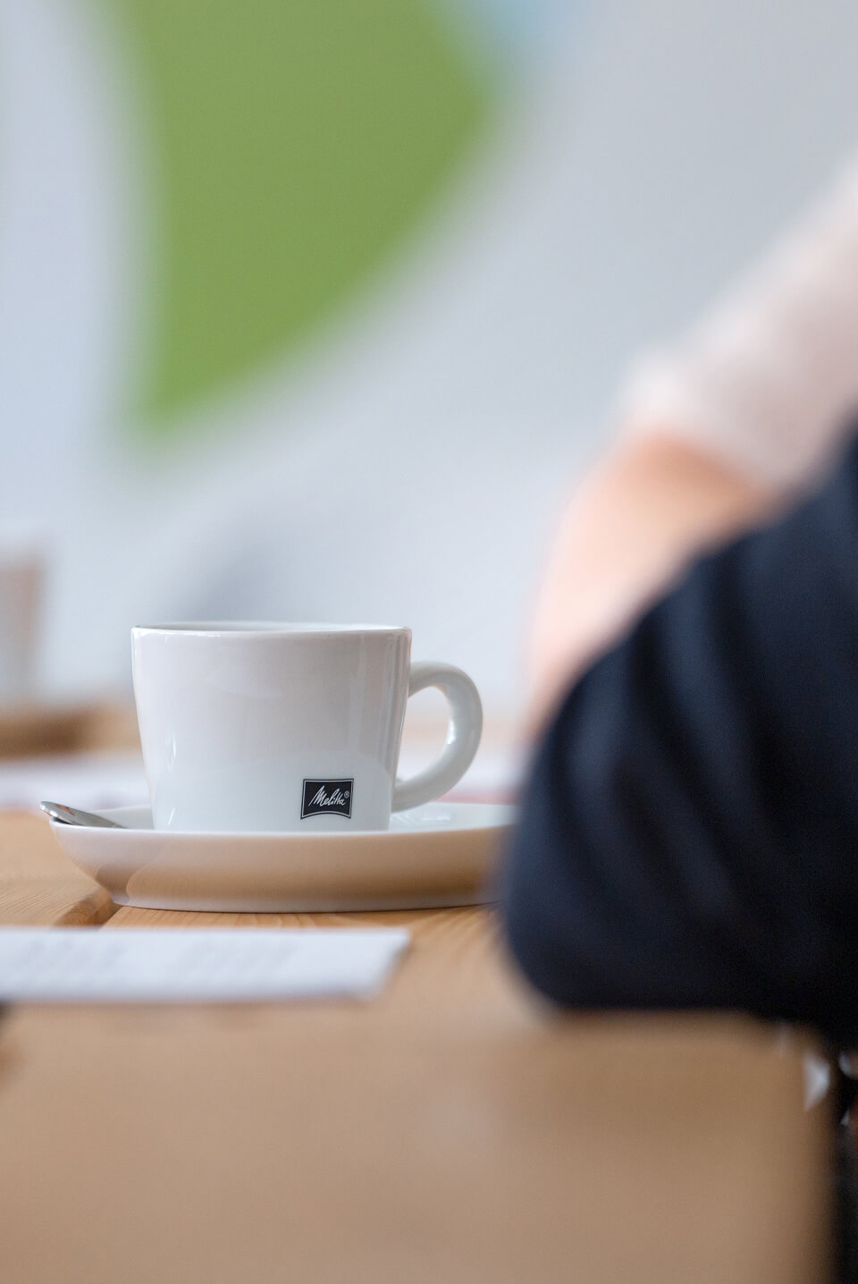 Close-up of a Melitta coffee cup on a saucer at a wooden table
