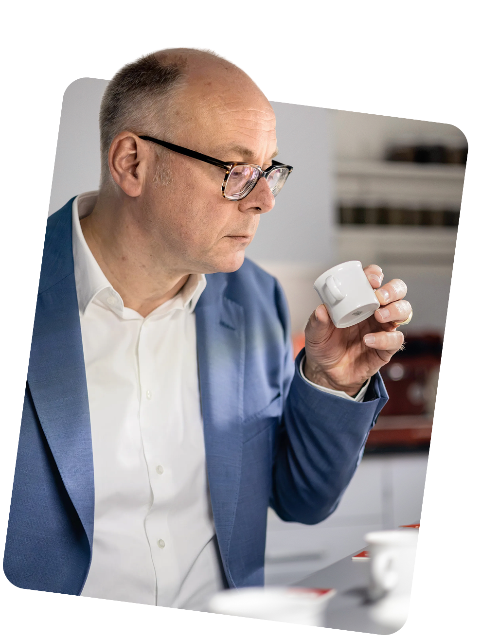 Protagonist pr&uuml;ft konzentriert eine wei&szlig;e Kaffeetasse bei einer professionellen Verkostung.